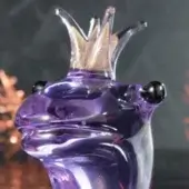 Glass frog sculpture, purple alexandrite, with black eyes and a golden glass crown, slender clear neck, studio display.