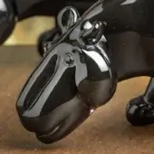 Black panther sculpture, polished resin, prowling pose with rounded head and glossy finish, set against a neutral wood background.