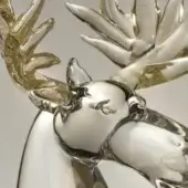 Glass reindeer sculpture, clear and gold, with intricately branched antlers and delicate facial features, set against a light gray backdrop.