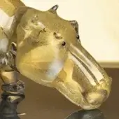 Glass hippopotamus sculpture, gold finish, detailed head with dark bead eyes and textured snout on ornate dark base.