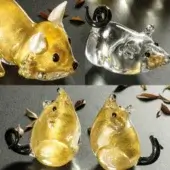 Blown glass cat & mice figurines, golden and transparent, with curled tails and glossy, handcrafted texture on a dark gray surface.
