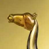 Amber glass camel sculpture with detailed head, translucent yellow neck, and swirling accents, set against a gold backdrop.