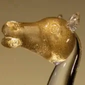 Glass camel sculpture with gold flecks, featuring a clear glass head and neck on a white opaque base.