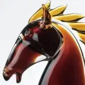 Glass horse head sculpture, amber and clear, stylized with elongated features and golden-yellow glass mane details on a white background.