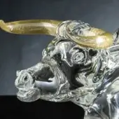 Glass ox head sculpture, clear with golden horns, detailed snout and textured surface, expressive blue-accented eyes, standalone decorative art.