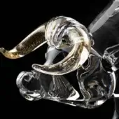 Glass ox sculpture, clear with gold horns, detailed form, transparent body, decorative collectible, black background, shimmering accents.