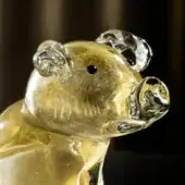Glass pig sculpture, golden translucent color, stylized rounded form with curled ears and textured interior.