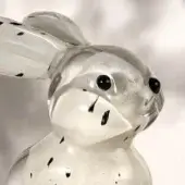 Glass rabbit sculpture with black inclusions, dynamic pose, clear form, stylized design, diffused lighting, white background.