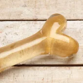 Gold resin bone sculpture on weathered whitewashed wood, featuring a translucent marbled finish and stylized rounded form.