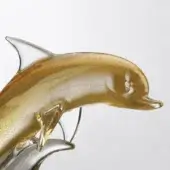 Glass dolphin sculpture, transparent with gold accents, dynamic curved form supported by delicate wire, smooth glossy finish.