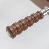 Wooden handle with cylindrical shape, dark brown walnut grain, textured ridges, and chrome shaft extension against a light beige backdrop.