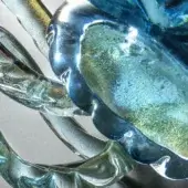 Glass sculpture, aquamarine and gold, featuring swirling translucent forms with rippled texture and internal bubbles.