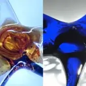 Glass sculptures, transparent amber and deep blue, featuring swirling organic patterns and curved abstract forms, studio shot.