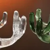 Glass cactus sculptures, clear and green, with ribbed texture and segmented branches, displayed against a reddish-brown backdrop.