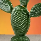 Glass cactus ficus sculpture, green with textured surface, against orange-to-yellow gradient backdrop, featuring yellow flower cluster.