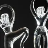 Transparent glass figurines, “infinite dance” series, depict reclining and standing figures with curved limbs and internal striations.