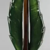 Green leaf sculpture with glossy finish, dark brown wood stem, angular edges, and subtle veining against a white backdrop.