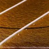 Arancio cast glass with amber-orange mottled texture, featuring embedded white metal rods and clear droplet details, illuminated with diffused light.