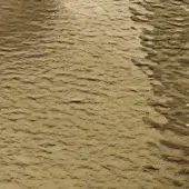 Bronze water texture with hammered glass effect, displaying irregular ripples and diagonal linear patterns under diffused lighting.