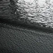 Textural composition of rippled water and weathered stone, featuring gray and black tones with dynamic light reflections and a smoked glass effect.