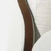 Curved seating upholstery, white leather with wood panel, textured weave and soft diffused lighting, modern minimalist design.