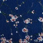 Embroidered fabric swatch, dark blue ground, red and white floral design with layered stitching, textured honeycomb background, SICIS branding.