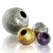 Mirrored decorative spheres, silver, gold, and purple, with cratered and speckled textures, arranged on a white reflective surface.