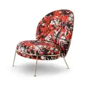 Armchair, red abstract fabric, rounded asymmetrical shape with gold metal legs and black feet, studio product shot.