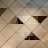 Geometric wall tiles in off-white beige with metallic sheen, featuring triangular pattern and voids revealing wood grain and abstract dark textures.