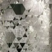 Grey mosaic surface with irregular fragments, displaying a geometric pattern of triangles, hexagons, and varied textures, set against a dark background.