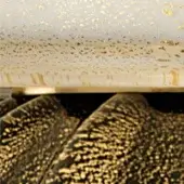 Beige and black textured surface with gold flakes, featuring a smooth beige upper section and sculpted black layers below.