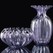 Amethyst glass vase and bowl with ribbed texture, scalloped rims, and translucent lavender-purple hue displayed on reflective black surface.