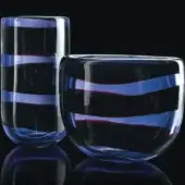 Glass vases with indigo, blue, and burgundy horizontal stripes on a black reflective surface, featuring cylindrical and rounded forms.