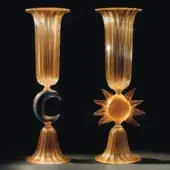 Amber glass vases with fluted tops and flared bases, one with crescent detail, one with sunburst design, vertical striations visible.