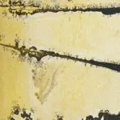 Distressed terrain texture with faded yellow and black cracks, showing a mottled, granular surface and porous material with scattered dark flecks.