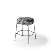 Low stool, black and white patterned fabric seat, gray metal crisscross legs, minimalist contemporary design, circular upholstered top.