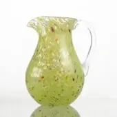 Green glass pitcher with speckled pattern, rounded body, flared spout, and curved handle, reflecting on a white surface.