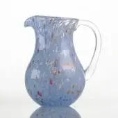 Glass pitcher, periwinkle blue, speckled with red, yellow, and blue inclusions; rounded body, curved handle, transparent finish.