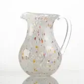 Glass pitcher with colorful speckled inclusions, rounded shape, and curved handle against a white backdrop.