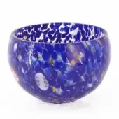 Blue glass bowl with spotted pattern, rounded shape, and glossy finish displayed on a white background in studio lighting.