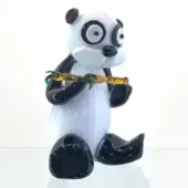 Glass panda sculpture, white with black markings, seated holding yellow-green bamboo, on textured black glass base, glossy finish.