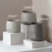 Ceramic vases, matte gray, cylindrical, tapered, and bulbous forms displayed on concrete cubes against a taupe wall.