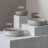 Ceramic bowls, light gray, displayed on concrete blocks against gray walls; shallow, elongated, and oval shapes with ridged textures.