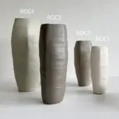 Ceramic vases, cylindrical shape, arranged in a row; colors include pale green, gray-green, dark brown, and beige with ridged texture.