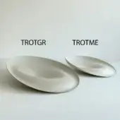 Ceramic bowls, light beige, oval shape; “TROTGR” left, larger, and “TROTME” right, with gently curved profiles and matte finish on gray surface.