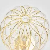 Glass table lamp with gold metal cage, pinecone textured shade, and visible Edison bulb within geometric rod structure.