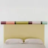 Upholstered bed with yellow headboard and segmented ‘rosary – structure’ featuring olive, pink, burgundy bands against a white backdrop.