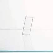 Clear glass cylinder on white surface, reflecting light and casting shadow, with subtle blue-green line accent and minimalist backdrop.