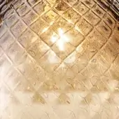 Textured glass lampshade with square grid pattern, warm brown tones, and central light reflection creating a starburst effect.