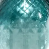 Textured glass surface displaying a teal and blue gradient with a diamond embossing and reflective highlights.